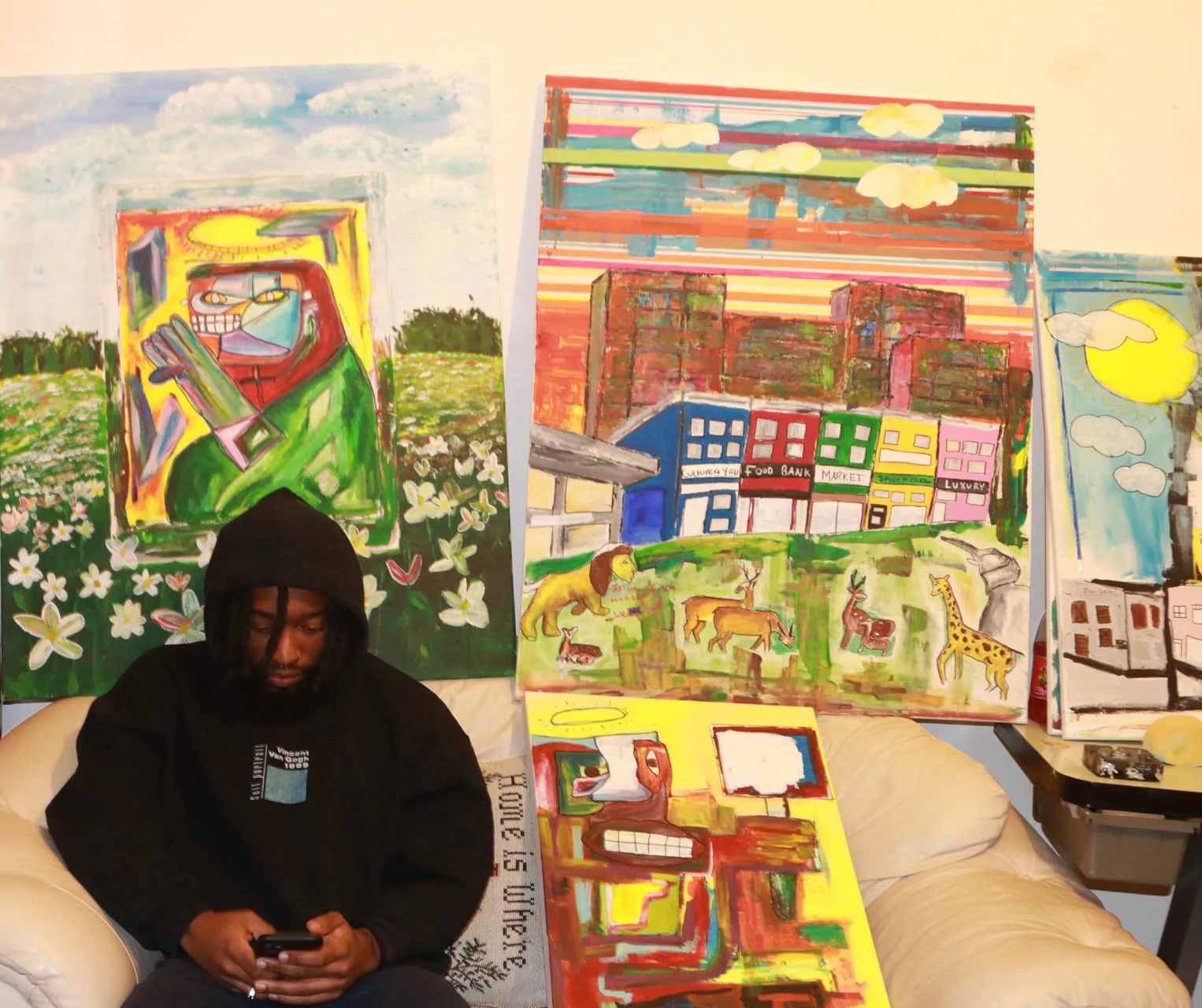 RXCVRDO seated in the studio in front of three large colourful paintings
